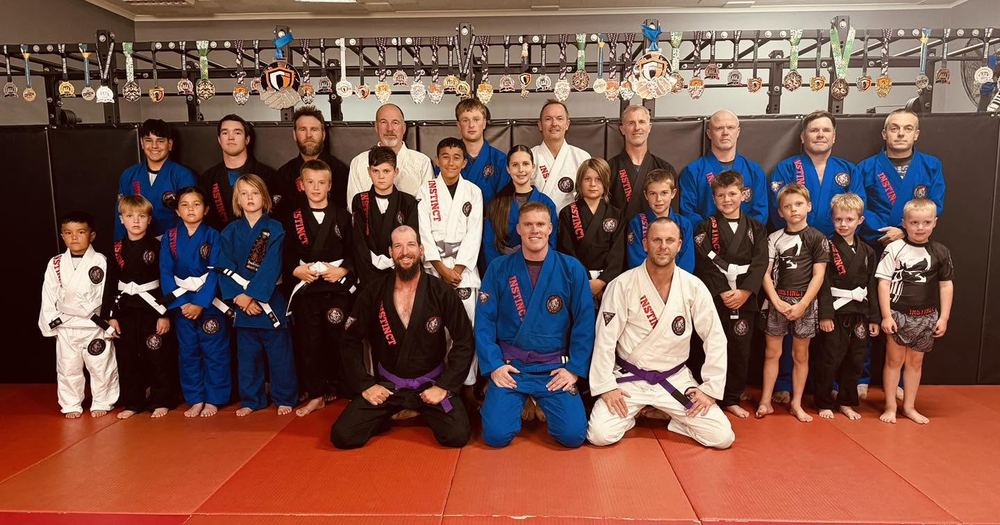 The Instinct BJJ adults and kids team lined up on the mats